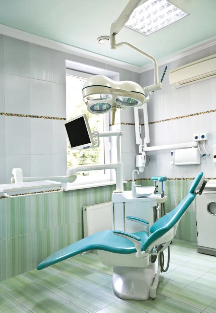 Bright treatment room with a teal dental chair