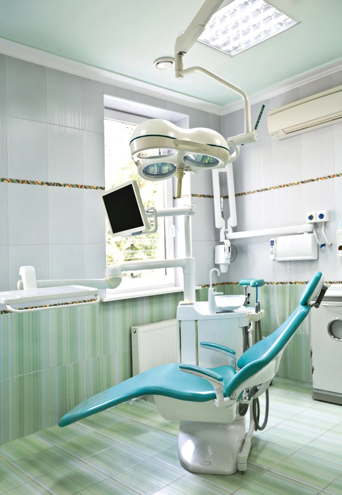 Bright treatment room with a teal dental chair